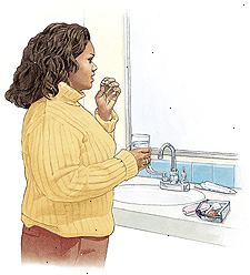 Kvinne står ved vasken på badet tar prevensjon pille.