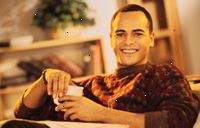Bilde av en ung mann smiler, holder en kopp kaffe