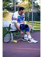 Bilde av en mann iført en kne-brace, spille tennis