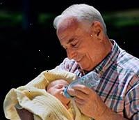 Bilde av en bestefar holdt sin nyfødte barnebarn, mate ham en flaske